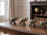 cinq éléphants posés sur une table devant une bibliothèque