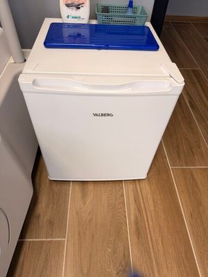 un petit réfrigérateur blanc avec un couvercle bleu dans une cuisine