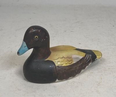 a small wooden duck sitting on a white surface