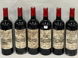 six bottles of wine are lined up in a row on a white surface
