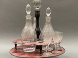 bottles and glasses on a tray with a candle holder on top of it