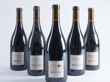 six bottles of wine are lined up in a row on a white surface