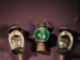 three old fashioned gas lamps are sitting on a purple cloth