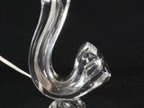 une lampe en verre transparent dont le pied a la forme d'un oiseau, sur fond noir