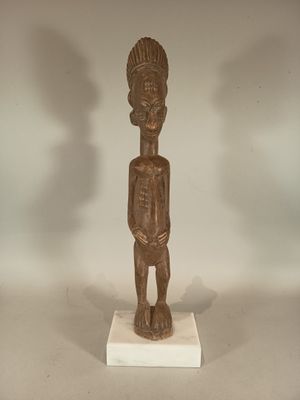 statue of a man standing on a white base with a shadow on the wall behind him