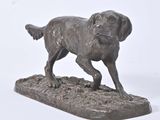 bronze statue of a dog on a rock on a white background