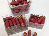 trois récipients en plastique remplis de cartouches de fusil rouges, posés sur une table blanche