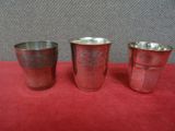 trois coupes en argent posées sur une nappe rouge