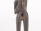 une vieille statue en bois représentant un homme les mains jointes sur la poitrine