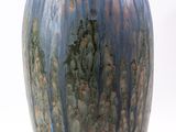 un vase bleu posé sur une surface blanche