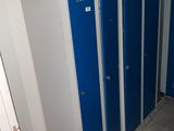 Plusieurs casiers bleus sont alignés les uns à côté des autres dans une salle de bains