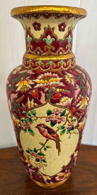 a vase that has a bird on it on a table