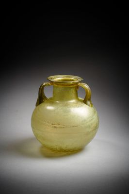 un vase en verre jaune posé sur une surface blanche, sur fond noir