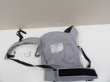 un porte-bébé gris et noir posé sur une table blanche, avec une étiquette dessus