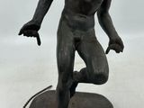 statue en bronze représentant un homme courant sur une corde posée sur une surface blanche