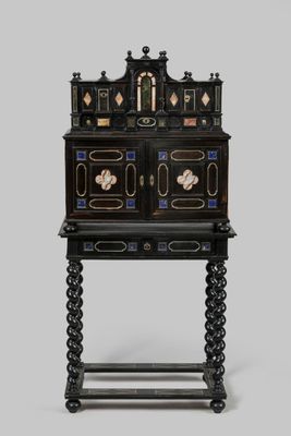 une armoire peinte en noir et or, surmontée de tiroirs