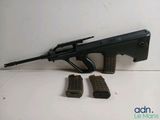 a close up of a rifle and four magazines on a table