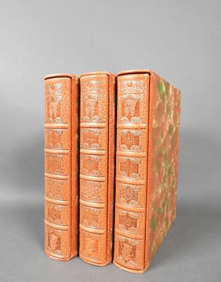 three orange books are stacked on top of each other on a gray surface