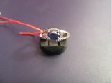 une bague avec une pierre bleue, montée sur un fil rouge
