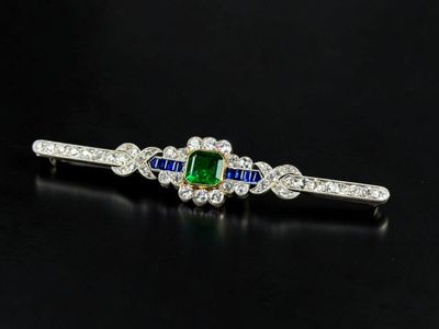 a close up of a green and white sapphire and diamond broochle