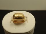 une photo d'une bague en or posée sur un socle blanc