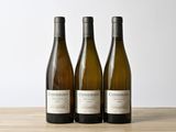 trois bouteilles de vin posées sur une table en bois