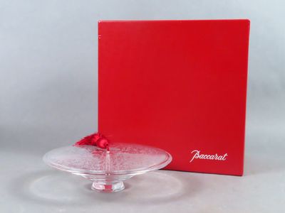 une assiette en verre vide, sur laquelle se trouvent une boîte rouge et un nœud rouge