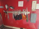 de nombreux couteaux et cuillères accrochés à un mur rouge