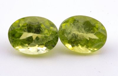 deux pierres précieuses vertes posées sur une surface blanche