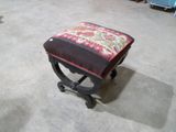 un petit tabouret recouvert d'un coussin rouge et vert
