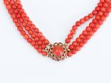 a close up of a necklace with red beads on a white background