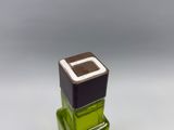 a green glass bottle with a brown square on top of it