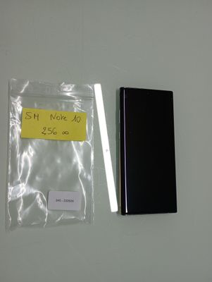 a black cell phone next to a yellow sticker on a white wall