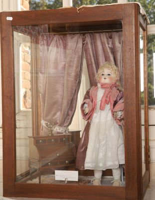 une poupée dans une vitrine, avec un rideau en arrière-plan