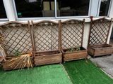 trois jardinières en bois contenant des plantes, posées sur l'herbe