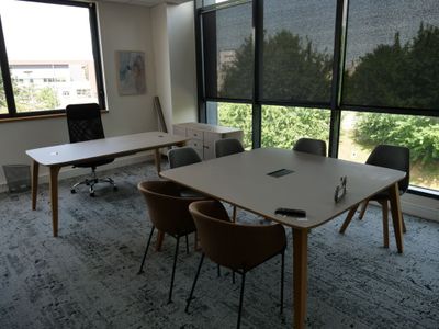 des tables et des chaises dans une pièce dotée de grandes fenêtres et offrant une vue sur les arbres