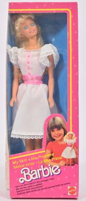 une poupée Barbie dans une boîte rose, vêtue d'une robe blanche et de chaussures roses
