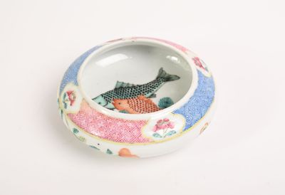a small bowl with a fish in it on a white surface