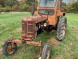 un vieux tracteur rouillé, abandonné dans un champ sous un ciel nuageux