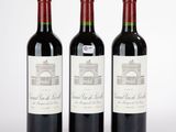 trois bouteilles de vin rouge posées l'une à côté de l'autre sur une surface blanche