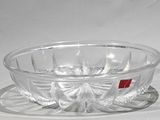 un saladier en verre et une assiette posés sur une surface blanche