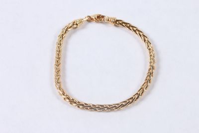 a close up of a gold bracelet on a white surface