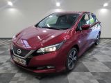 La Nissan Versa rouge est garée sur un sol à damier.