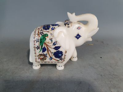 un éléphant blanc avec un motif bleu et vert sur le dos