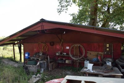 an image of a red shed with a lot of junk on the ground