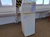 a white refrigerator in the corner of a room with a window