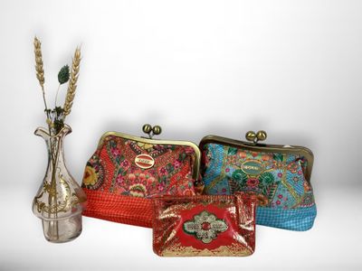 several purses are lined up next to a vase with a flower in it