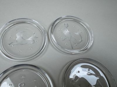 three clear glass dishes with a bird design on them sitting on a table