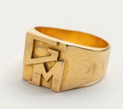 un gros plan d'une bague en or sur laquelle figure la lettre « m »
