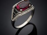a ring with a ruby stone and diamonds on a black surface
